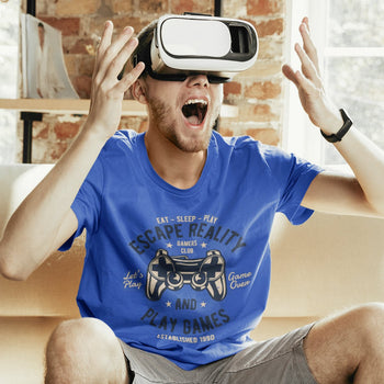 Gamer guy with gaming tee of game controller artwork adorned by typography elements saying 'Escape Reality and Play Games'.