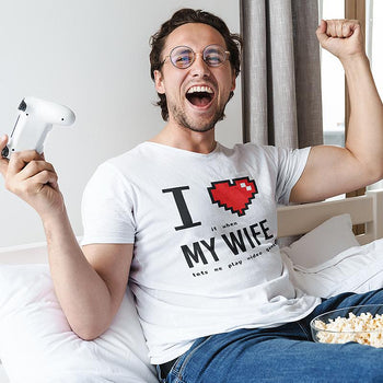 Gamer husband wearing funny gaming tee that actually says 'I Love (it when) My Wife (lets me play video games)'.