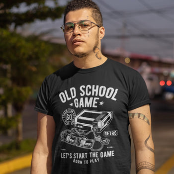 Man with retrogaming t-shirt illustrating retro NES console and typography elements that say 'Old School Game, Born to Play'.